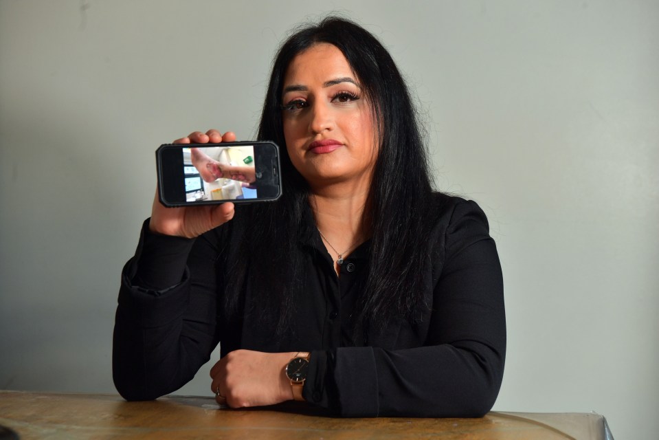 a woman holds up a cell phone with a picture of a person 's hand on it