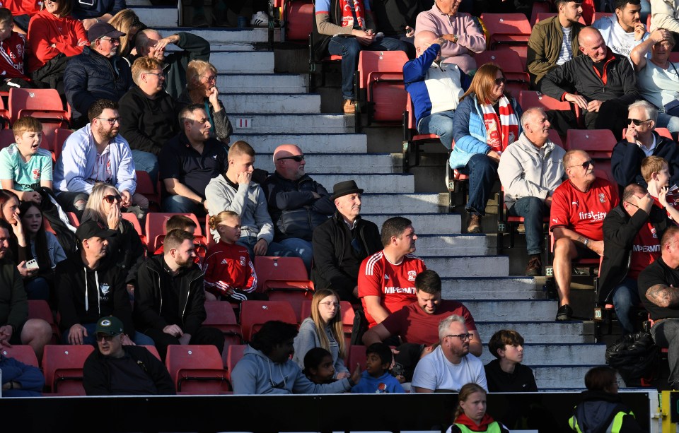 a group of people sitting in a stadium with one wearing a red shirt that says firestone