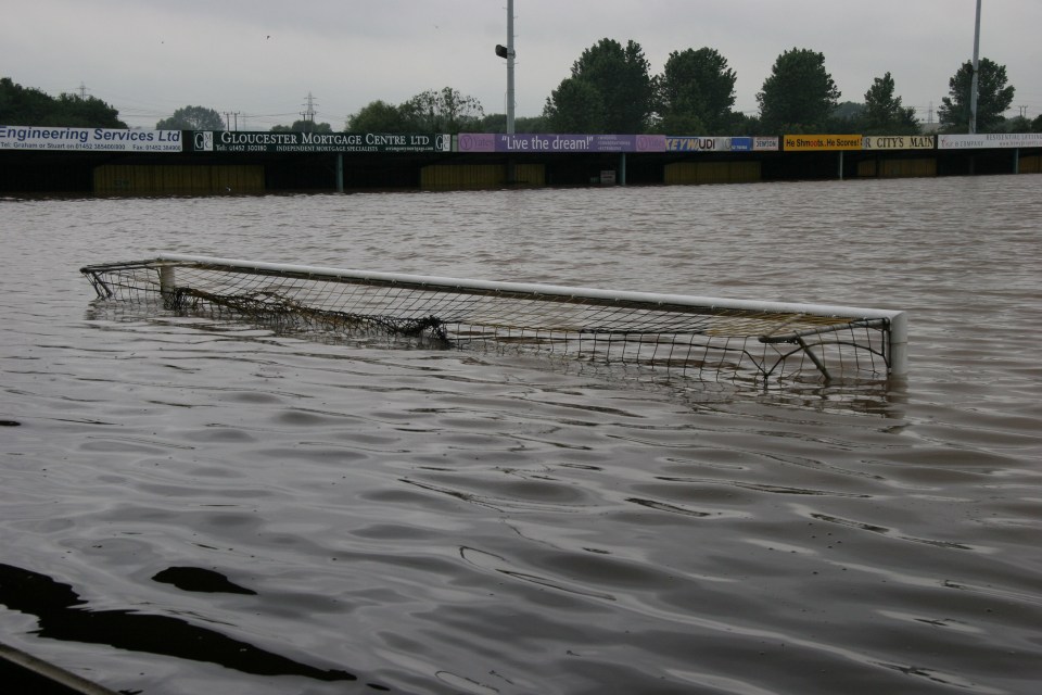 a flooded soccer field with a sign for gloucester mortgage centre