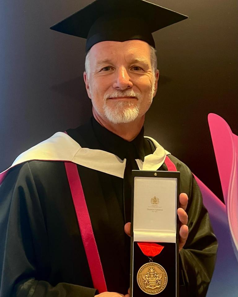 a man in a graduation cap and gown is holding a medal