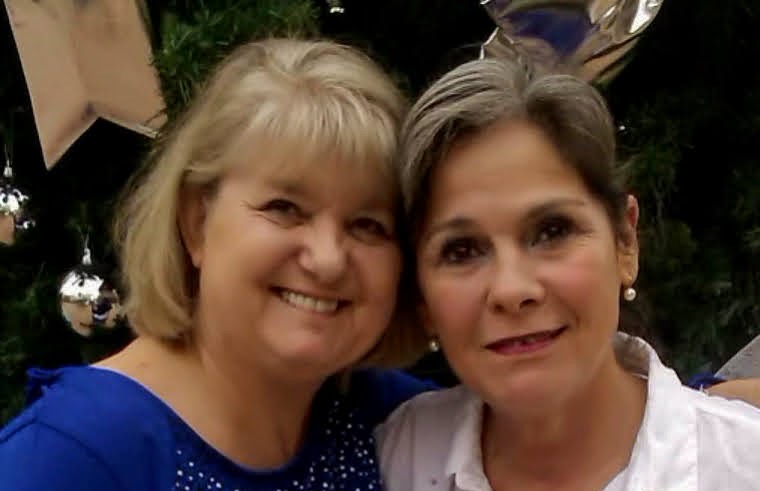 two women are posing for a picture in front of a christmas tree .