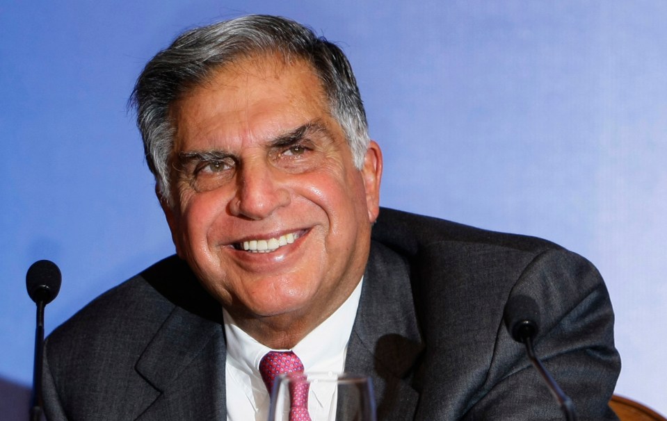 a man in a suit and tie smiles in front of a microphone