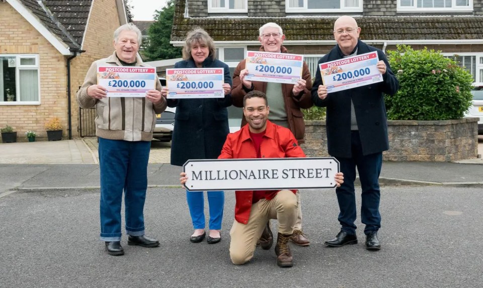 a group of people holding up a sign that says millionaire street