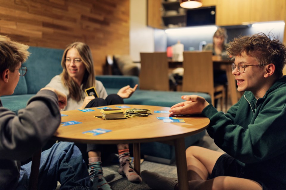 a group of people sit around a table playing a card game