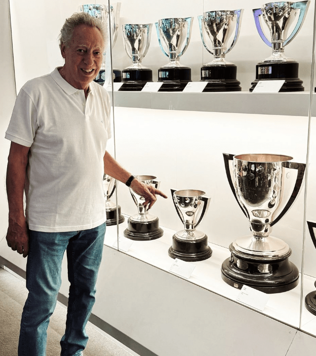 a man stands in front of a display of trophies including one with the letter y on it