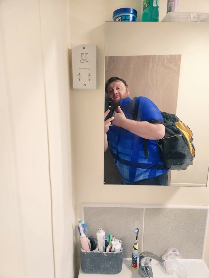 a man in a blue shirt is taking a picture of himself in a bathroom mirror