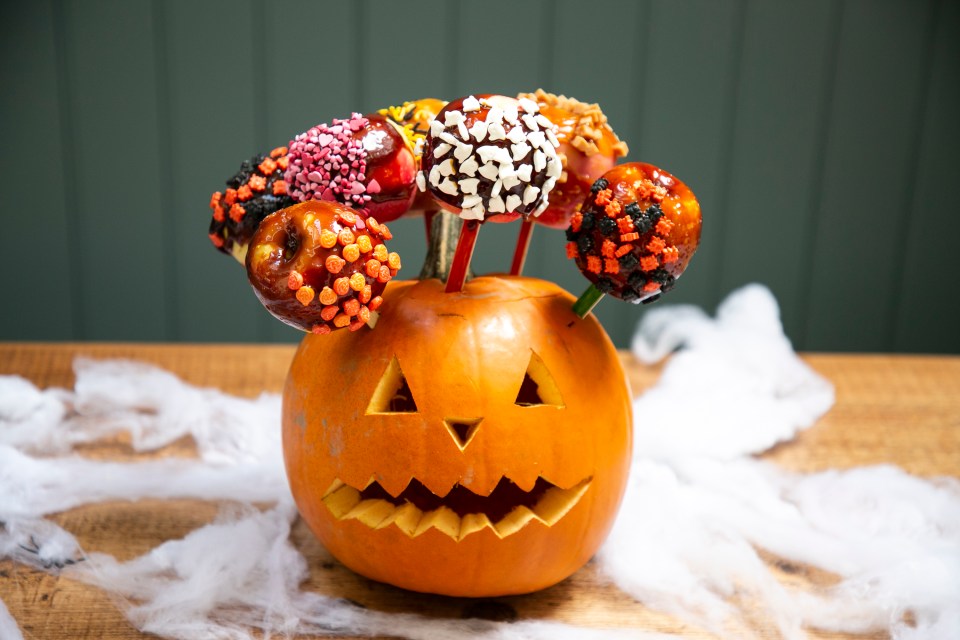 a pumpkin with a face carved into it is filled with donuts on sticks