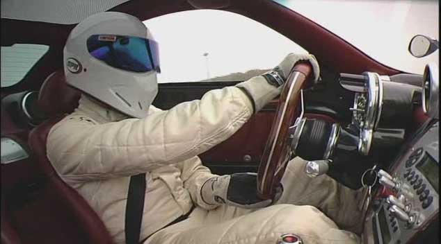 a man wearing a helmet and gloves is driving a car .