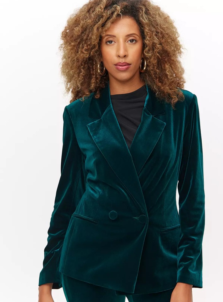 a woman with curly hair is wearing a green velvet jacket