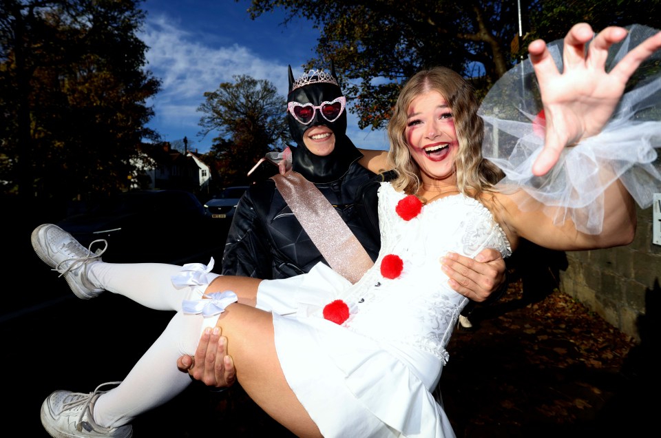 a man in a batman costume is carrying a woman in a wedding dress