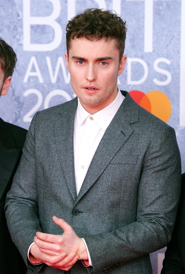 a man in a suit is standing in front of a sign that says brit awards