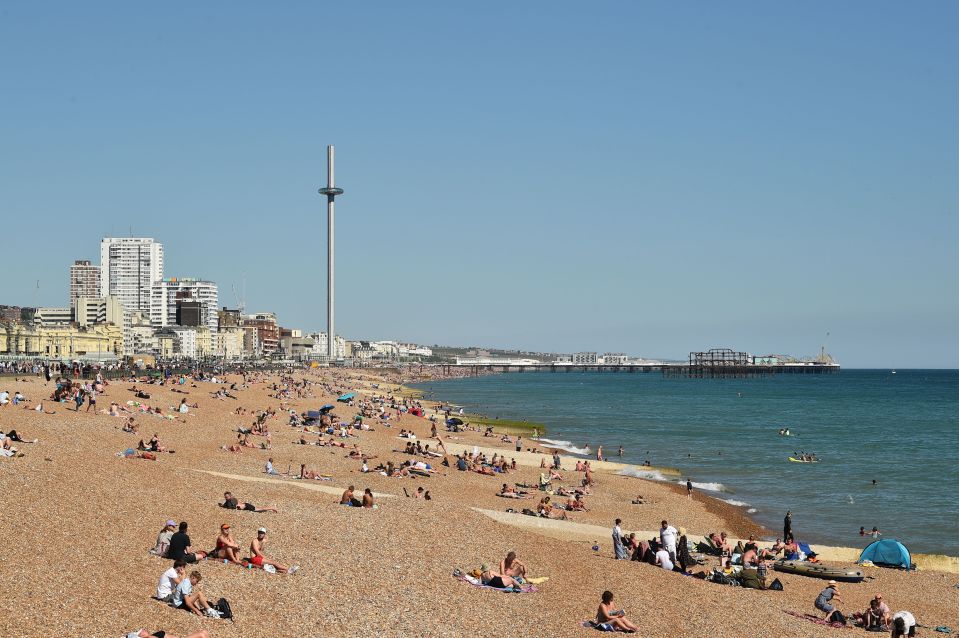 a crowded beach with a tall tower in the background