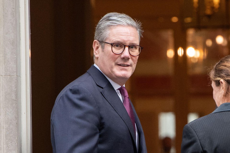 a man wearing glasses and a suit stands in a doorway