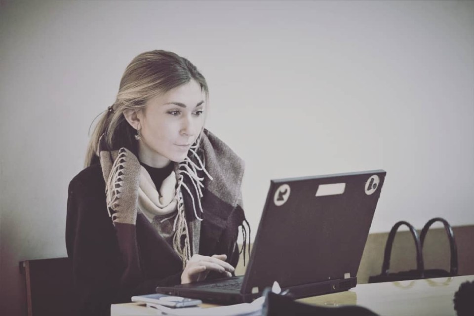 a woman with a scarf around her neck is using a laptop