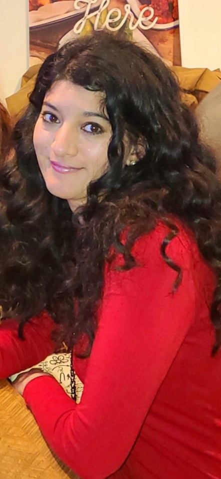 a woman with curly hair is smiling in front of a sign that says here