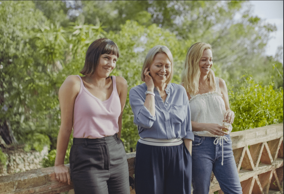 three women are standing next to each other and one is talking on a cell phone