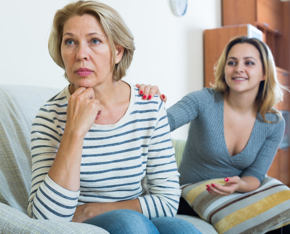 a woman sitting on a couch with her arm on another woman 's shoulder