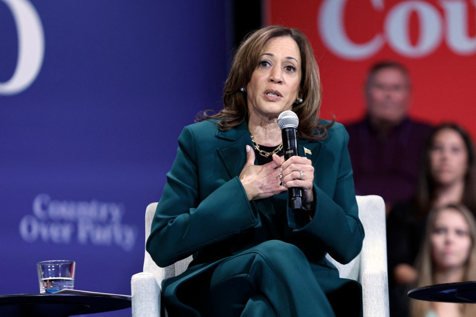 a woman speaking into a microphone in front of a sign that says country over party