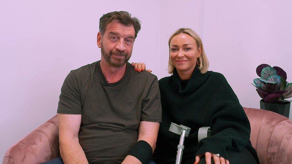 a man with crutches sits next to a woman with red nails