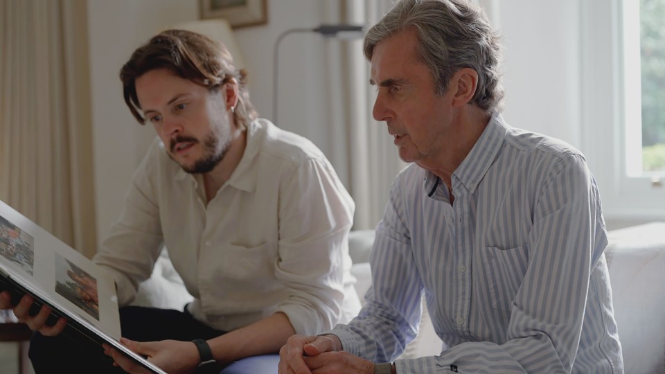 two men are looking at a photo album together