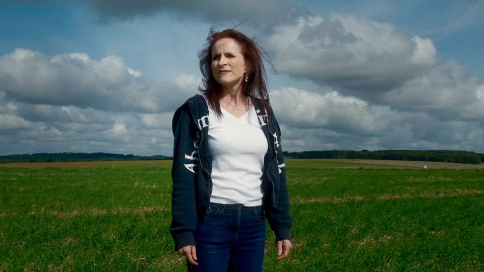 a woman stands in a field wearing a sweatshirt that says abercrombie & fitch