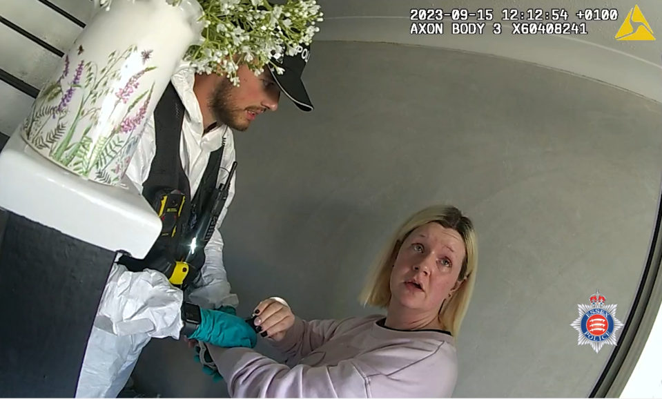 a police officer is talking to a woman in front of a vase of flowers