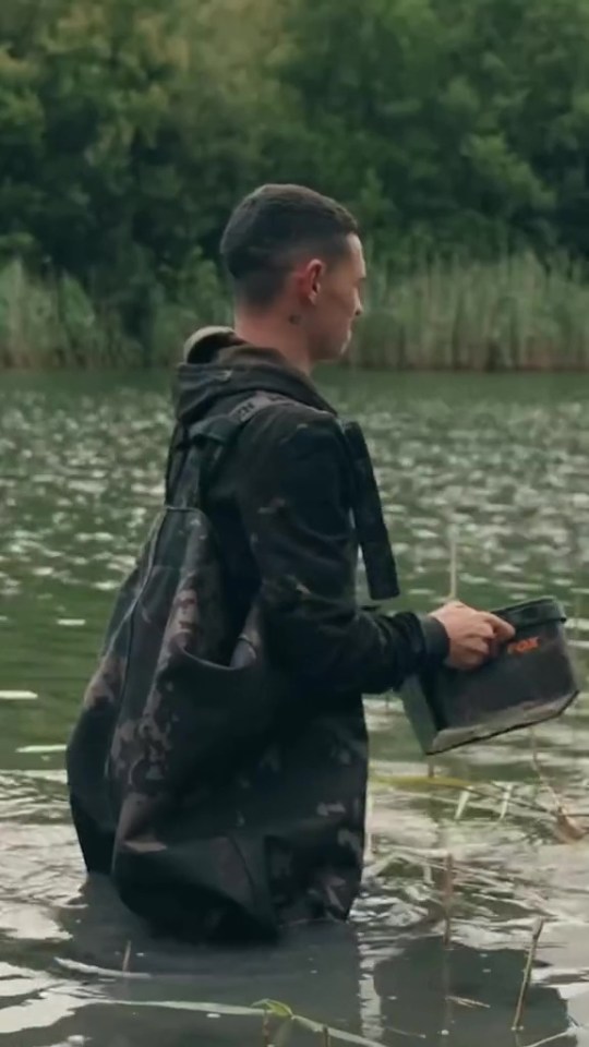 a man is standing in the water with a bag that says fox on it