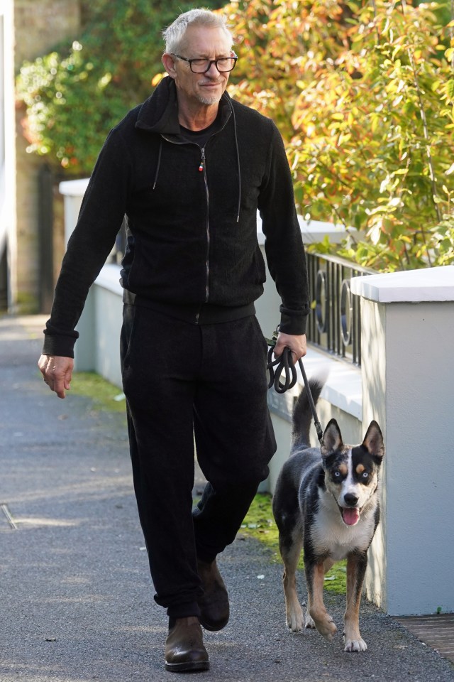 a man wearing glasses is walking a dog on a leash