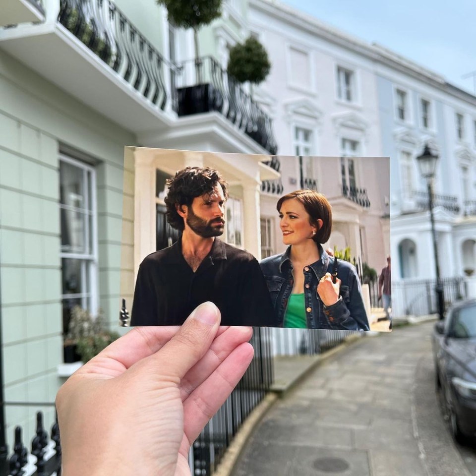 a person is holding a picture of a man and woman in front of a building