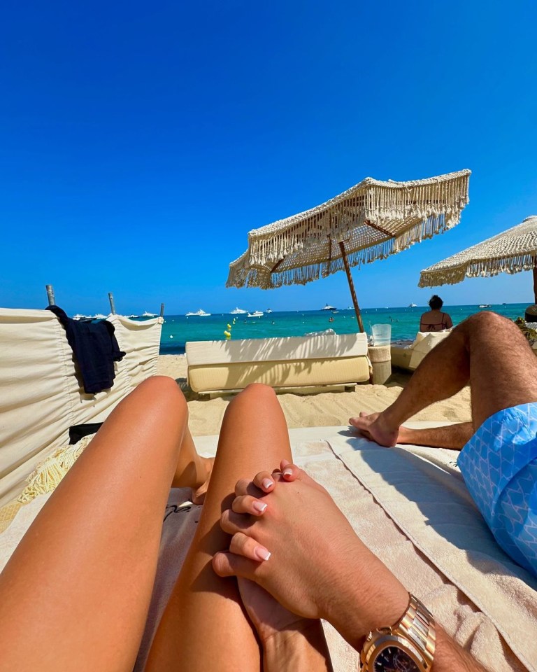 a man and a woman laying on a beach holding hands