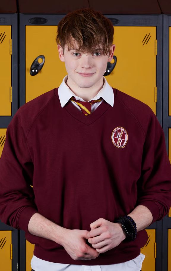 a young man wearing a maroon sweater with a badge that says ' williams ' on it