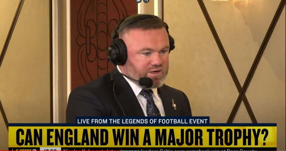 a man in a suit and tie is talking into a microphone with the words can england win a major trophy below him