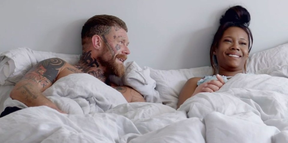 a man with tattoos on his face is laying next to a woman