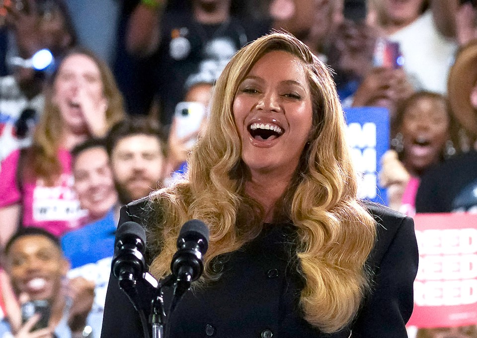 a woman laughs while speaking into a microphone in front of a crowd