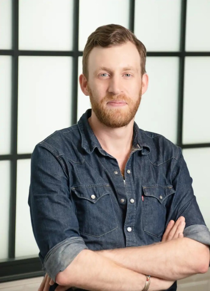 a man in a denim shirt with his arms crossed