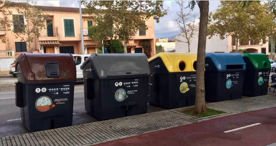 a row of recycling bins are lined up on a sidewalk