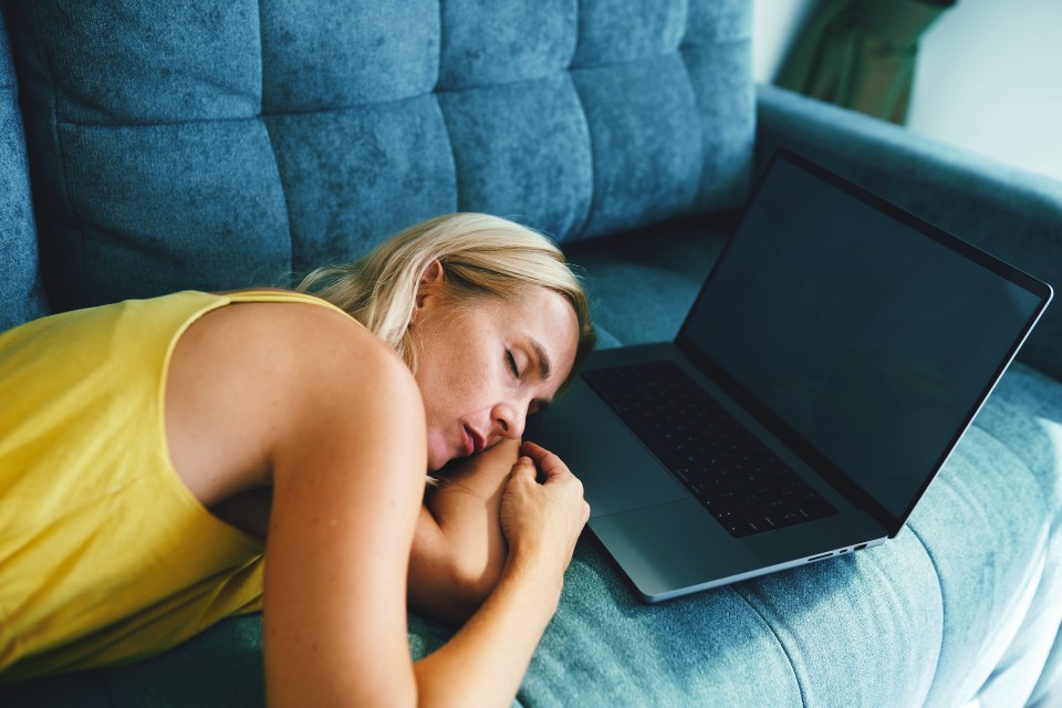 a woman sleeping on a couch next to a laptop