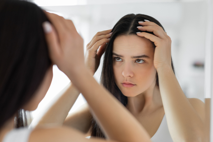 a woman is looking at her hair in the mirror