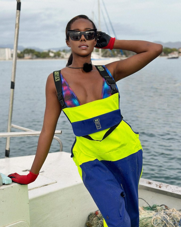 a woman standing on a boat wearing a yellow and blue outfit that says ' gm ' on it