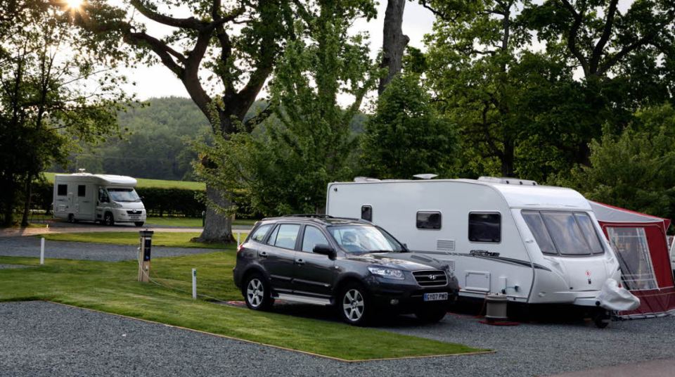 a black suv is parked next to a caravan that says ' swift ' on it