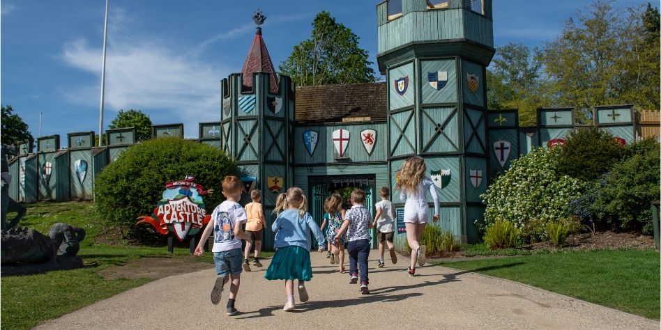 a group of children are walking towards the adventure castle