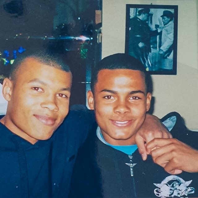 two young men are posing for a picture with a picture of a police officer on the wall behind them