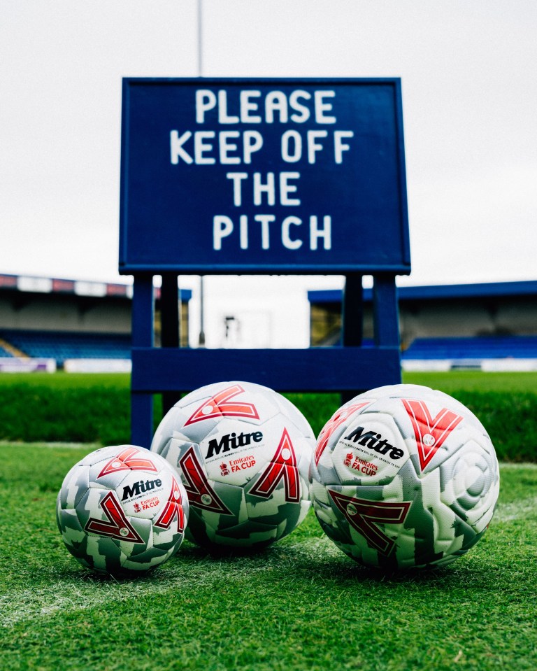 three mitre soccer balls on a field in front of a sign that says please keep off the pitch