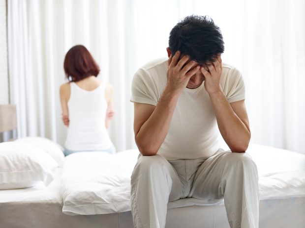 a man sits on a bed with his head in his hands