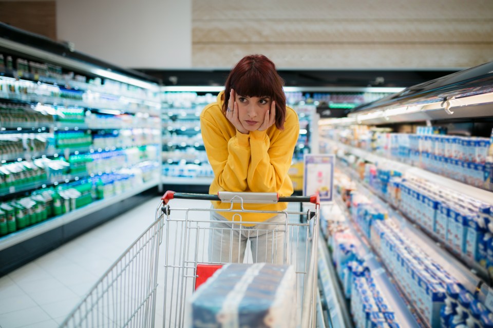 a woman in a yellow sweatshirt is shopping in a grocery store