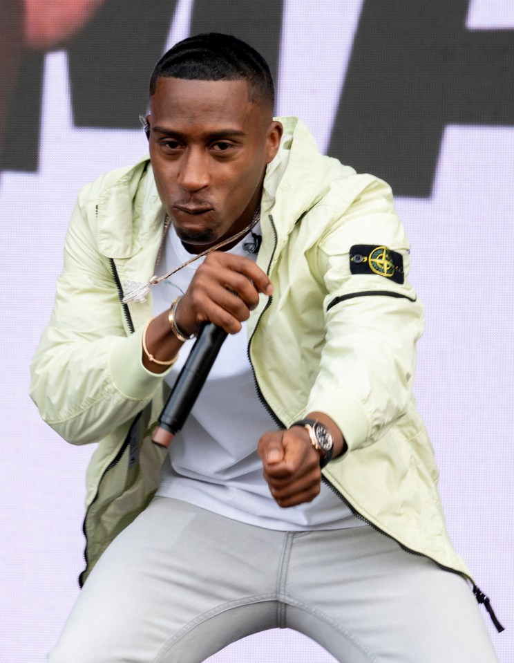 a man wearing a stone island jacket is singing into a microphone