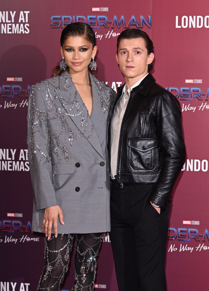 a couple standing on a red carpet that says spider-man on it