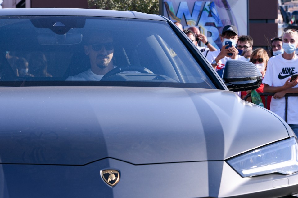 a man in a nike shirt is driving a lamborghini