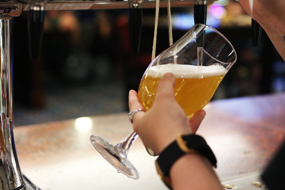 a person pouring a glass of beer from a tap