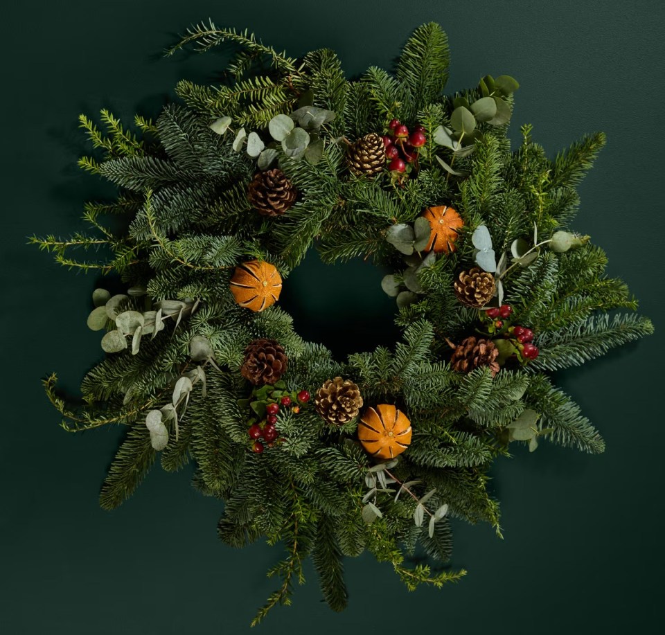 a christmas wreath with pine cones berries and oranges